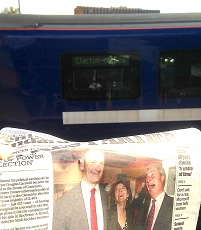 Zeitung mit Carswell und Farage drauf vor Zug, der nach Clacton-on-Sea geht.